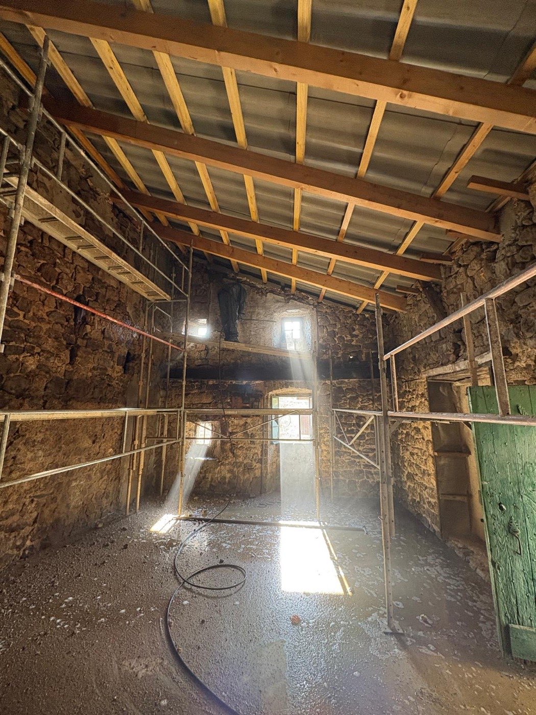Charpente neuve vue de l’intérieur d’une grange en pierre en cours de rénovation en Ardèche